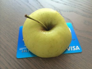 An apple sits on to of a Visa credit card