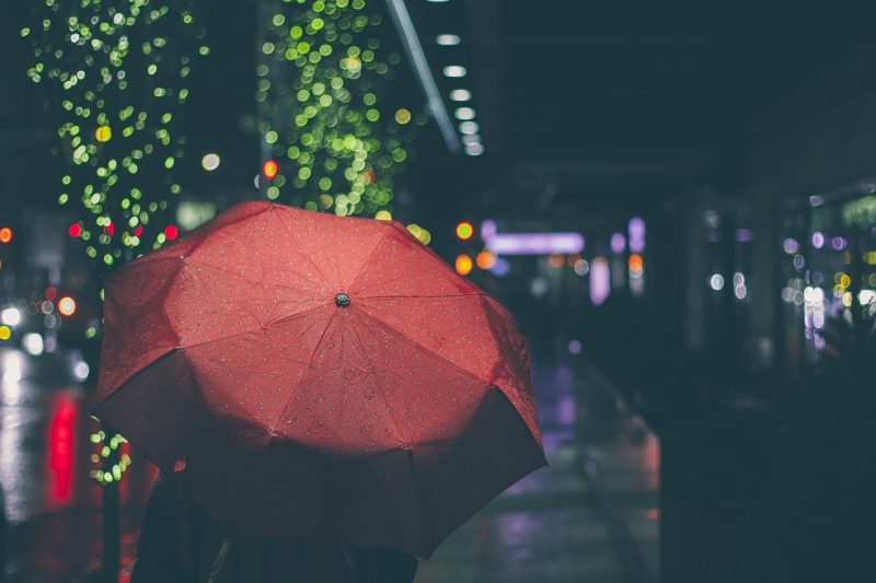 Red umbrella against a rainy city background at night