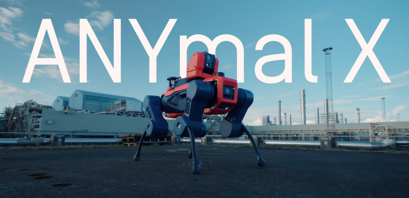 An image shot of the ANYmal X, a dog-like four legged robot with a red body, grey legs, with ANYmal X in white letters displayed over a blue sky background and a warehouse building in the background.
